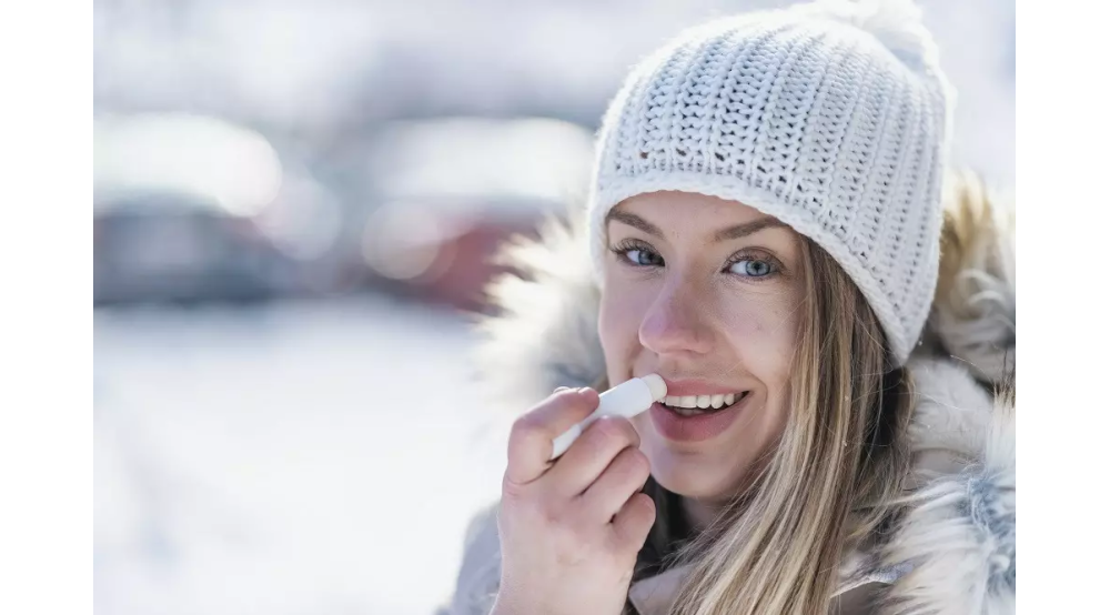 Kobieta smaruje usta pomadką ochronną